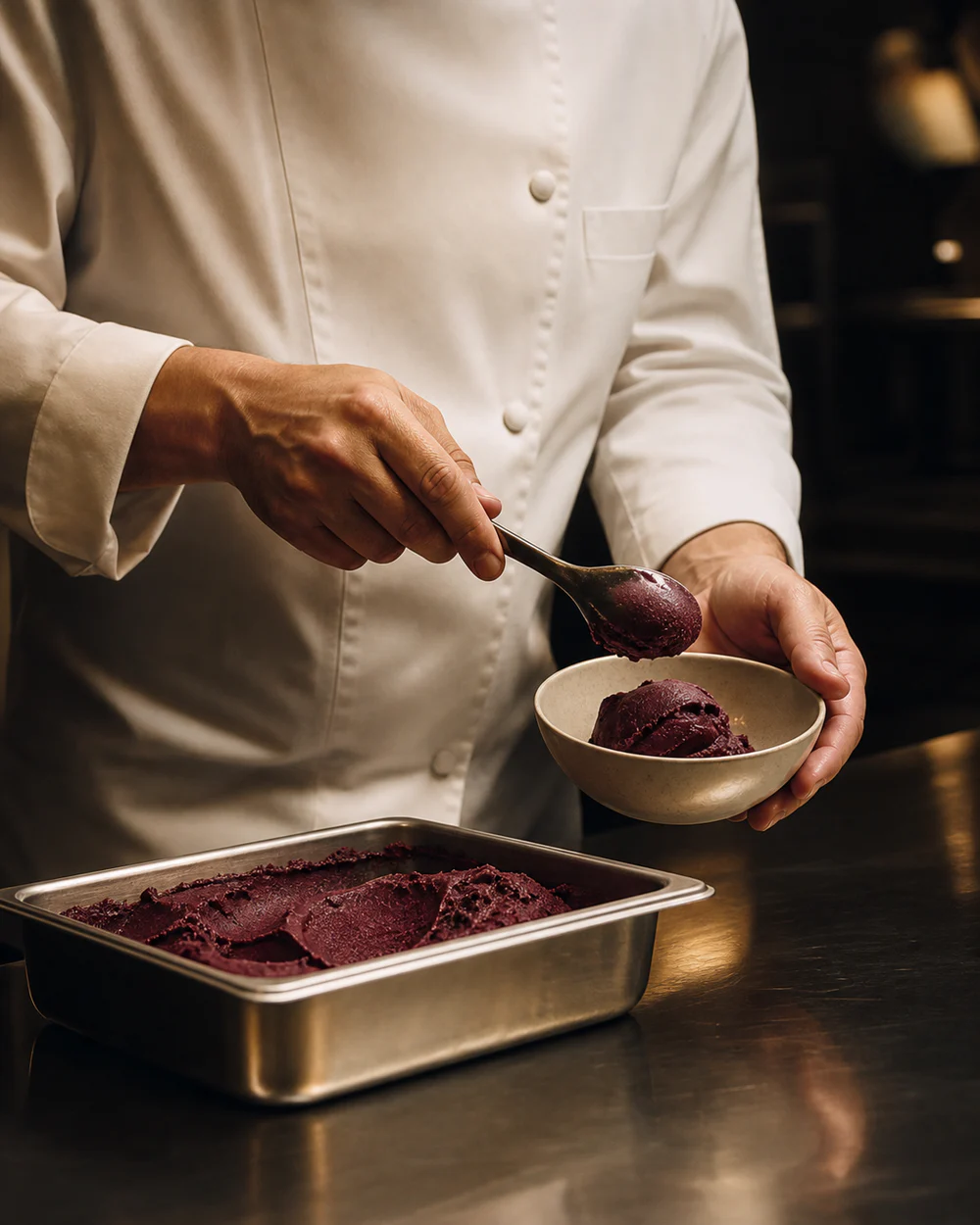 A hotel chef serving açaí sorbet into a tasting bowl.